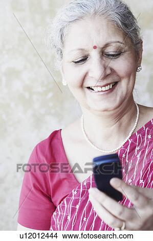 Close-up of a mature woman holding a mobile phone View Large Photo Image Picture - Close-up of a mature woman holding a mobile phone. Fotosearch