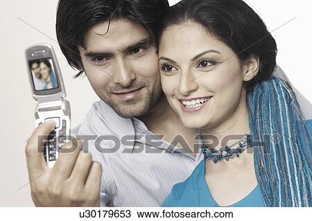 Close-up of a young couple taking a photograph of themselves View Large Photo Image Stock Image - Close-up of a young couple taking a photograph of themselves. Fotosearch