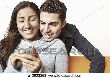 Close-up of a young couple using a mobile phone View Large Photo Image Stock Photo - Close-up of a young couple using a mobile phone. Fotosearch