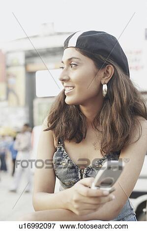 Close-up of a young woman holding a mobile phone View Large Photo Image Stock Photo - Close-up of a young woman holding a mobile phone. Fotosearch
