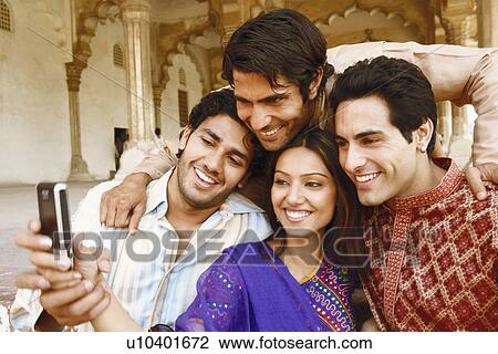 Close-up of three young men and a young woman looking at a mobile phone and smiling, Agra, Uttar Pradesh, India View Large Photo Image Stock Image - Close-up of three young men and a young woman looking at a mobile phone and smiling, Agra, Uttar Pradesh, India. Fotosearch