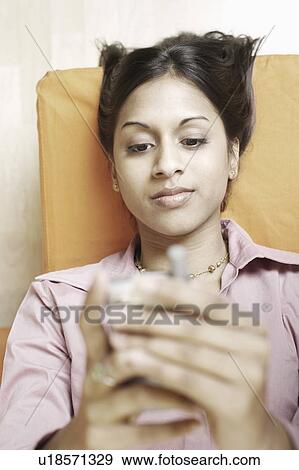 Stock Photo - High angle view of a young woman holding a mobile phone. Fotosearch