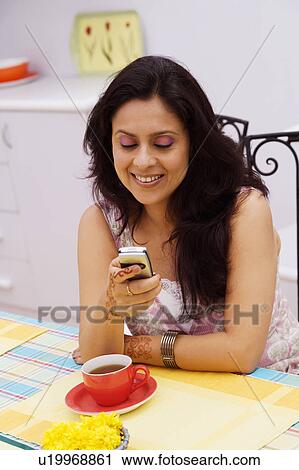 Mid adult woman operating a mobile phone View Large Photo Image Stock Image - Mid adult woman operating a mobile phone. Fotosearch