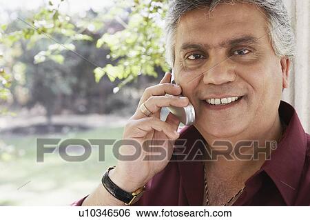 Stock Photograph - Portrait of a mature man talking on a mobile phone. Fotosearch