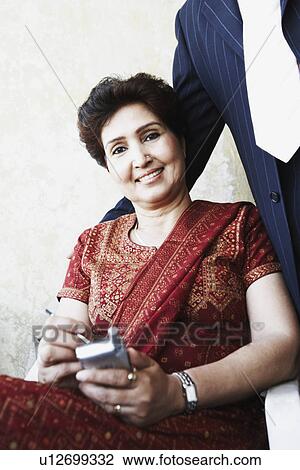 Stock Image - Portrait of a mature woman holding a mobile phone. Fotosearch