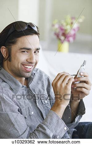 Stock Image - Portrait of a young man using a mobile phone with a digitized pen. Fotosearch
