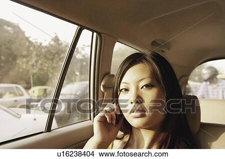 Picture - Portrait of a young woman talking on a mobile phone in a car. Fotosearch