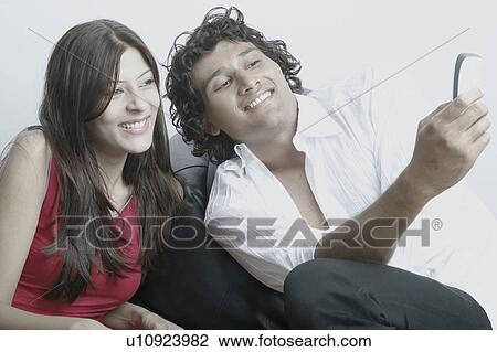 Stock Image - Young couple looking at a mobile phone. Fotosearch