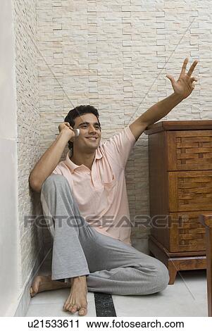 Stock Image - Young man talking on a mobile phone and smiling. Fotosearch