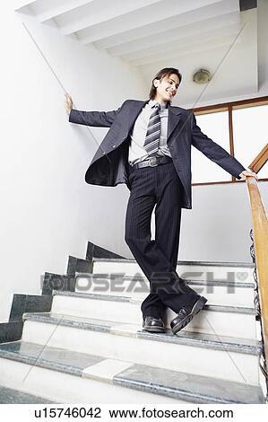 Businessman standing on the staircase with his arms outstretched View Large Photo Image Stock Image - Businessman standing on the staircase with his arms outstretched. Fotosearch