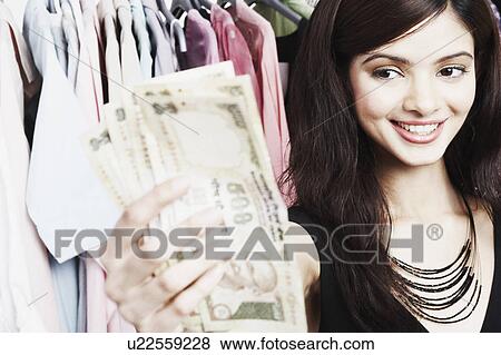 Close-up of a young woman holding banknotes in a clothing store View Large Photo Image Stock Photo - Close-up of a young woman holding banknotes in a clothing store. Fotosearch