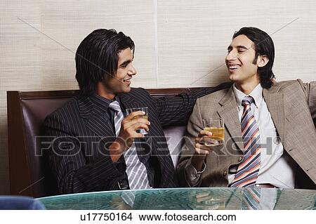 Picture - Close-up of two businessmen holding glasses of whiskey. Fotosearch