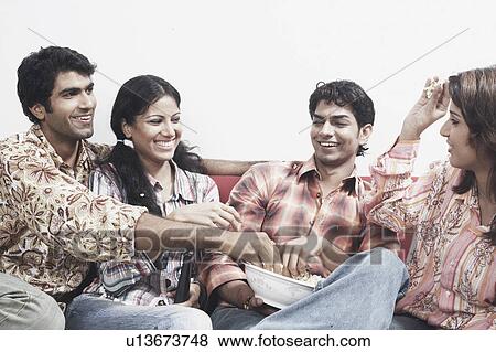Stock Photo - Close-up of two young men and two young women throwing popcorn on each other. Fotosearch