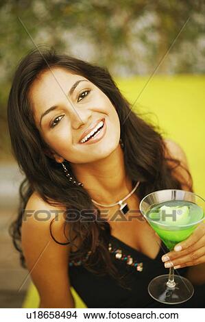 Portrait of a young woman holding a glass of cocktail View Large Photo Image Picture - Portrait of a young woman holding a glass of cocktail. Fotosearch
