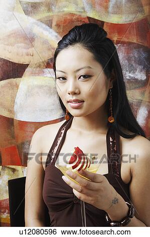 Stock Photograph - Portrait of a young woman holding a martini glass. Fotosearch