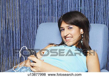 Stock Photo - Portrait of a young woman listening to an MP3 player. Fotosearch