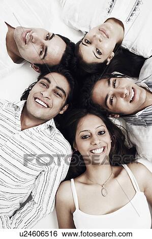 Stock Photograph - Portrait of three young men and two young women lying down. Fotosearch