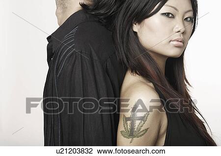 Stock Image - Side profile of a young couple standing back to back. Fotosearch