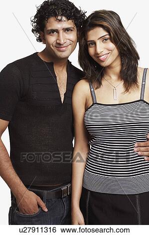 Stock Photograph - Portrait of a young couple standing and smiling. Fotosearch