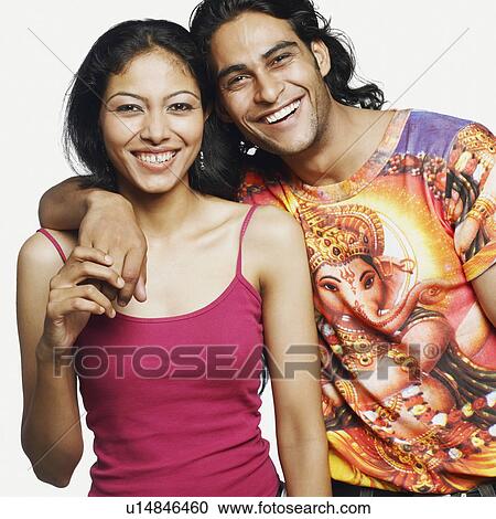 Stock Image - Portrait of a young man standing with his arm around a mid adult woman and smiling. Fotosearch