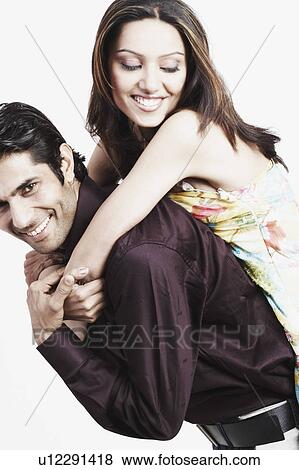 Stock Photo - Portrait of a young woman riding piggyback on a young man. Fotosearch