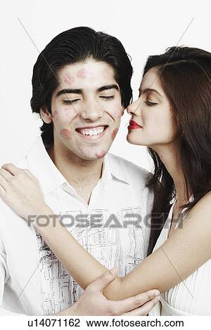 Stock Image - Side profile of a young woman kissing a young man. Fotosearch