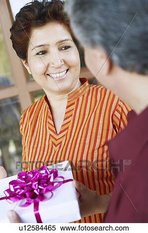 Stock Photography - Close-up of a mature man giving a birthday present to a mature woman. Fotosearch