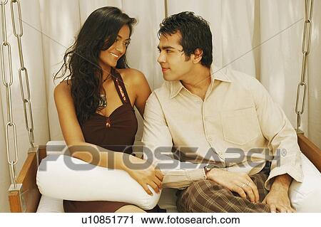 Close-up of a young couple sitting on a swing and looking at each other View Large Photo Image Stock Image - Close-up of a young couple sitting on a swing and looking at each other. Fotosearch