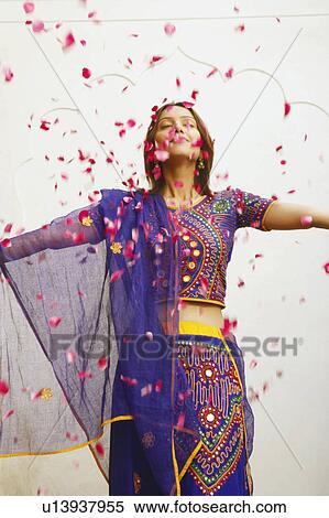 Close-up of a young woman standing with rose petals falling around her View Large Photo Image Stock Photography - Close-up of a young woman standing with rose petals falling around her. Fotosearch