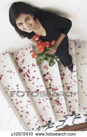 Stock Image - High angle view of a young woman holding a bouquet of flowers. Fotosearch