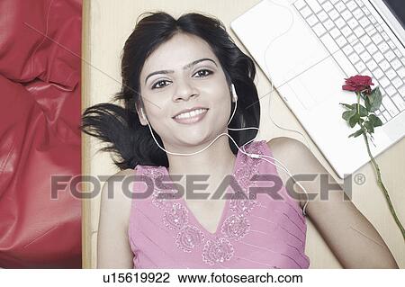 Stock Image - High angle view of a young woman listening to an MP3 player. Fotosearch
