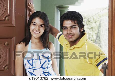 Stock Image - Portrait of a young couple standing in a doorway and smiling. Fotosearch