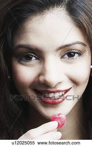 Stock Photography - Portrait of a young woman holding candy. Fotosearch
