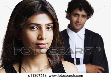 Portrait of a young woman with a male lawyer standing behind her View Large Photo Image Stock Photo - Portrait of a young woman with a male lawyer standing behind her. Fotosearch