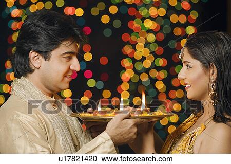 Side profile of a young couple holding a plate of religious offerings and looking at each other View Large Photo Image Stock Image - Side profile of a young couple holding a plate of religious offerings and looking at each other. Fotosearch