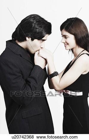 Stock Photo - Side profile of a young man kissing a young woman's hand. Fotosearch