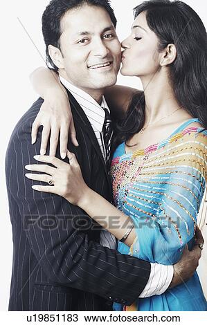 Stock Image - Side profile of a young woman kissing a young man. Fotosearch