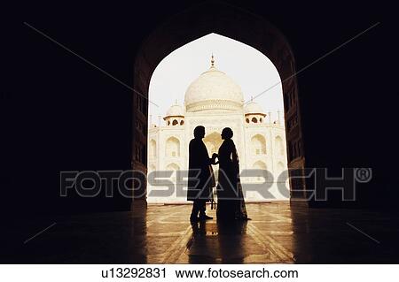 Stock Image - Silhouette of a couple standing in front of a mausoleum, Taj Mahal, Agra, Uttar Pradesh, India. Fotosearch