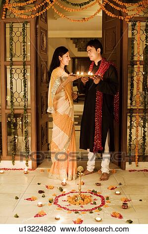 Young couple holding oil lamps in a plate View Large Photo Image Stock Image - Young couple holding oil lamps in a plate. Fotosearch