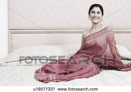 Stock Photo - Young woman sitting on the bed. Fotosearch