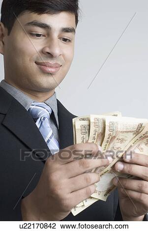 Stock Image - Close-up of a businessman counting Indian currency notes. Fotosearch