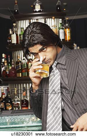 Close-up of a businessman drinking whiskey at a bar counter View Large Photo Image Stock Image - Close-up of a businessman drinking whiskey at a bar counter. Fotosearch
