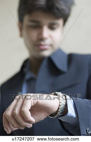 Stock Photo - Close-up of a businessman looking at his wristwatch. Fotosearch