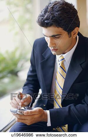 Stock Photograph - Close-up of a businessman using a personal data assistant. Fotosearch