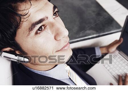 Close-up of a businessman wearing a hands free device and using a laptop View Large Photo Image Stock Image - Close-up of a businessman wearing a hands free device and using a laptop. Fotosearch