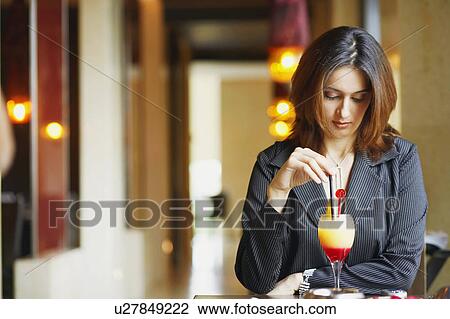 Stock Image - Close-up of a businesswoman sitting in a restaurant with a glass of pinacolada. Fotosearch