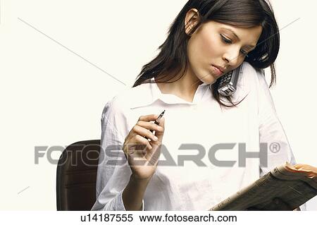 Close-up of a businesswoman talking on a cordless phone and looking at a newspaper View Large Photo Image Stock Photography - Close-up of a businesswoman talking on a cordless phone and looking at a newspaper. Fotosearch