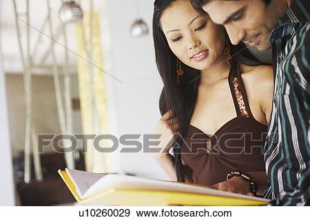 Stock Photo - Close-up of a young couple reading a menu card. Fotosearch