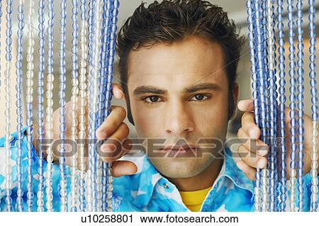 Portrait of a young man peeking through a beaded curtain View Large Photo Image Stock Image - Portrait of a young man peeking through a beaded curtain. Fotosearch