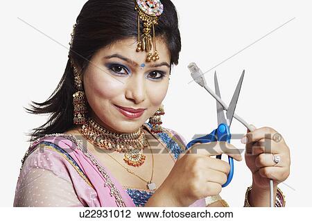 Stock Image - Portrait of a young woman cutting a network computer cable. Fotosearch